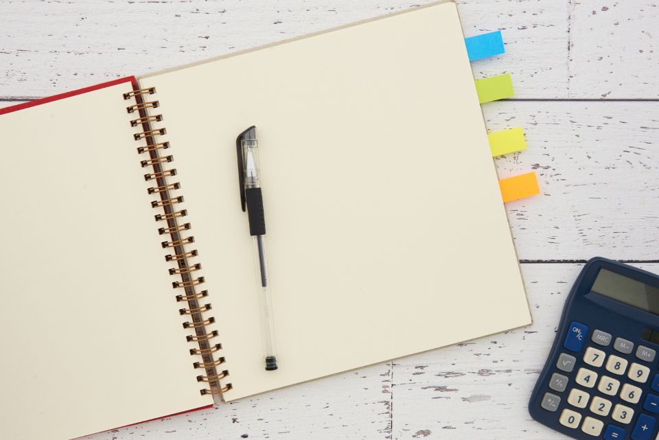 Un carnet ouvert avec un stylo et une calculatrice posés sur un bureau clair, pour estimer le retour sur investissement