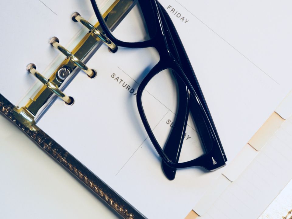 Un agenda de semaine ouvert avec une paire de lunettes posée dessus