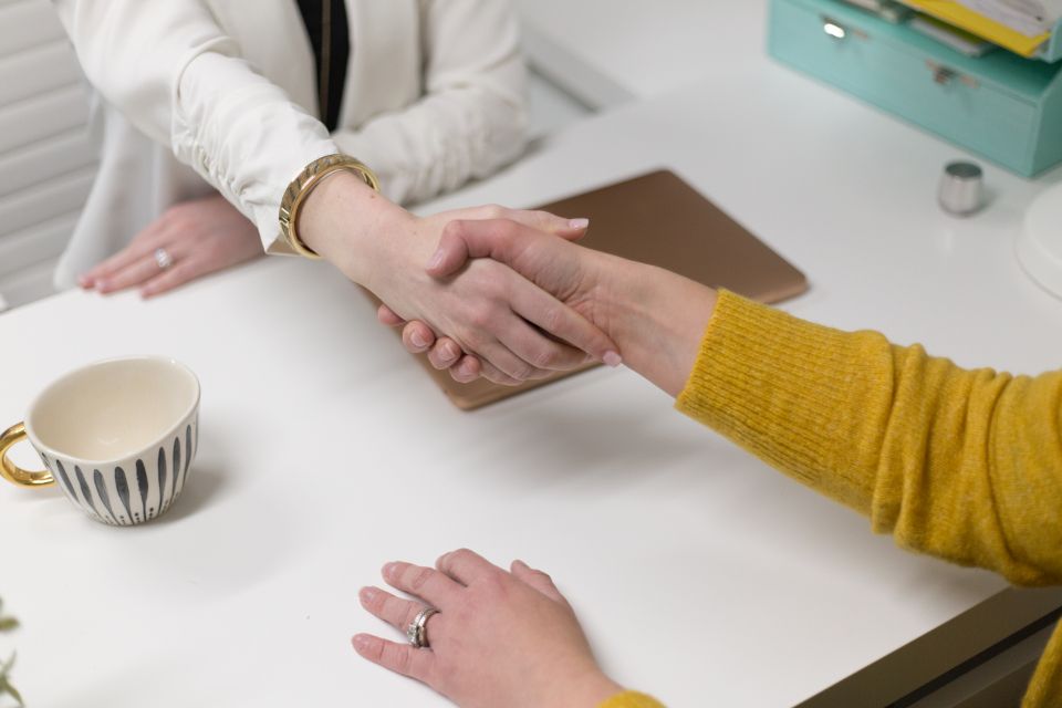 Deux personnes se serrent la main au-dessus d'un bureau, concluant un accord