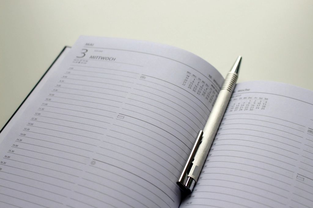 Un agenda papier ouvert avec un stylo posé dessus, pour illustrer le suivi des dates d'échéance