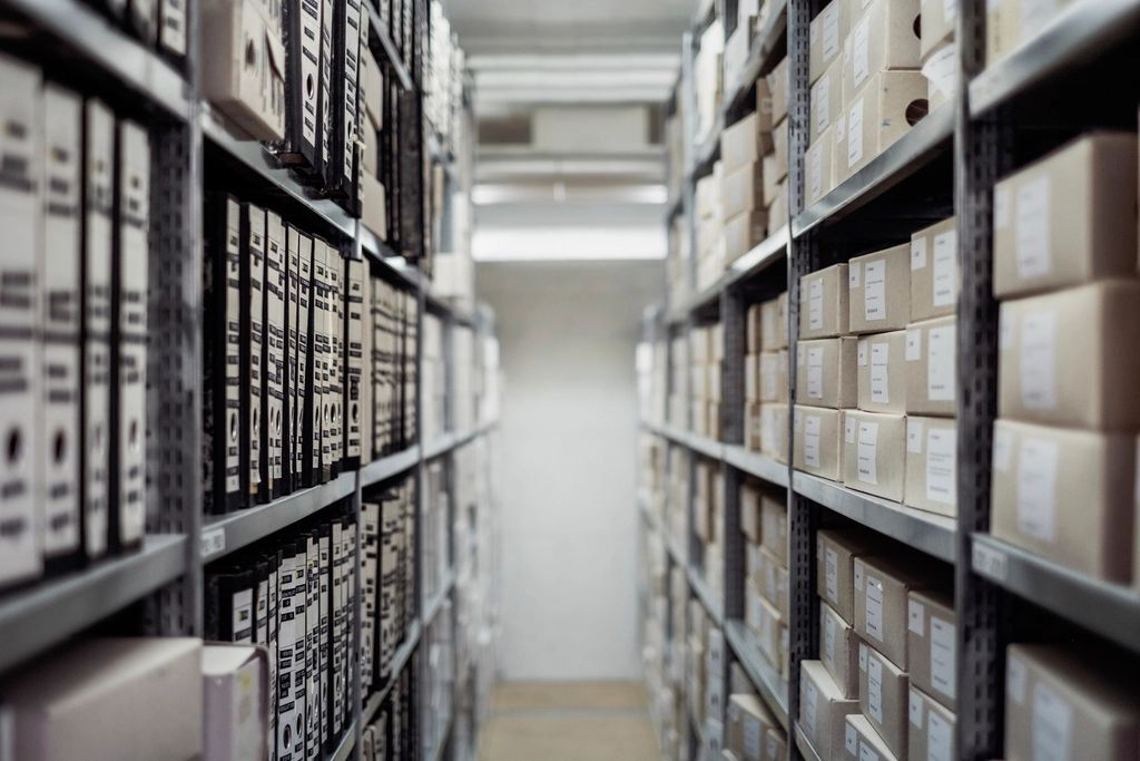 Allée d'archives remplie de classeurs et de boîtes de dossiers sur des étagères